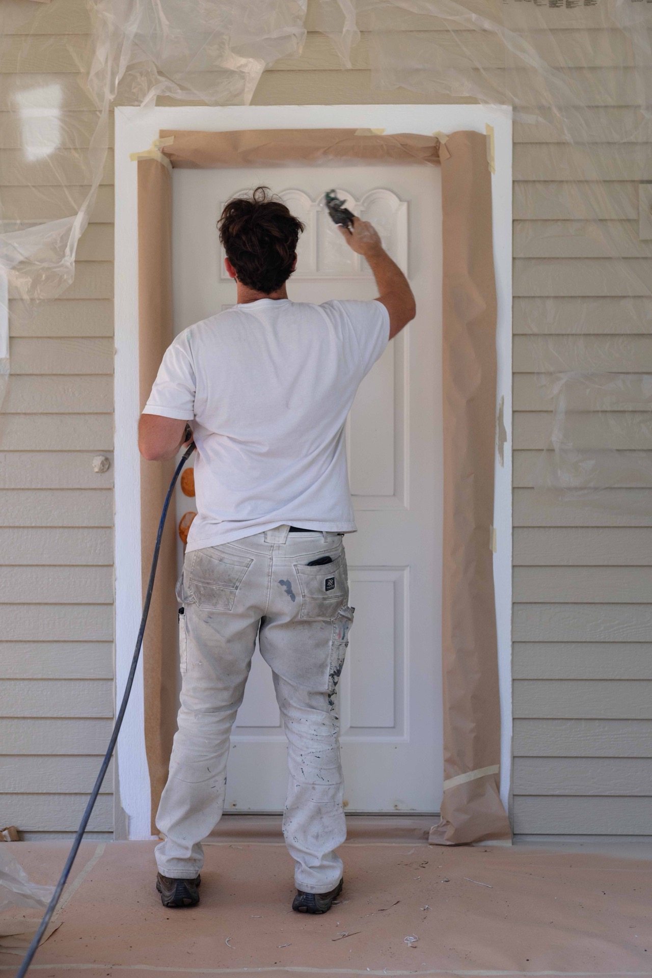 Spray-painting a masked entry door at a Hayden, Idaho home