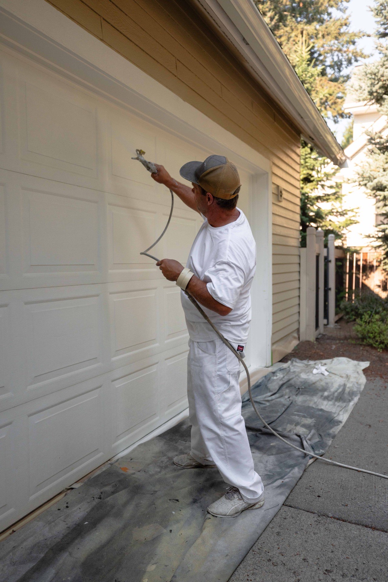War Horse painter spray-painting a garage door at a Hayden, Idaho home