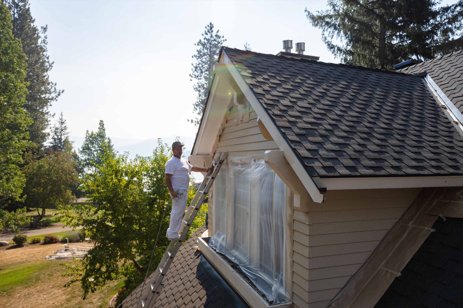 War Horse painter working on a dormer during an exterior repaint near Hayden Lake in Hayden, Idaho