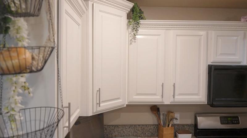 Close-up of upper cabinets after refinishing with crisp white paint and crown molding