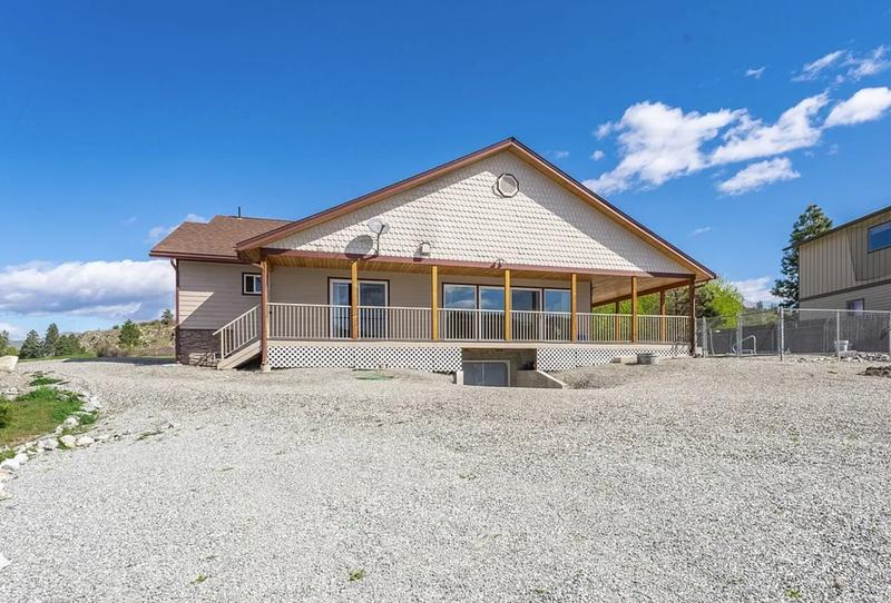 Rear view of house with beige siding and deck before painting