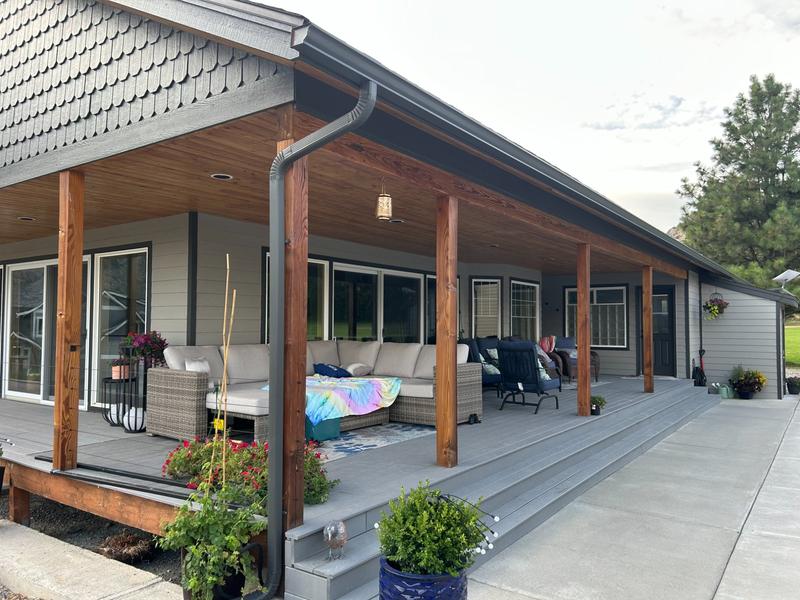Covered back porch with dark gray siding and natural wood stained posts
